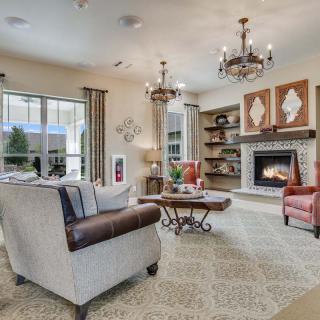 A cozy living room with elegant furnishings, a fireplace, and large windows.