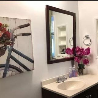 A well-decorated bathroom with a mirror, sink, and floral arrangement.