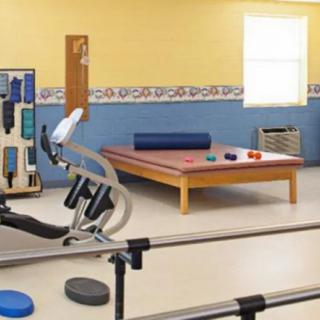 A well-equipped physical therapy room with exercise equipment and a therapy table.