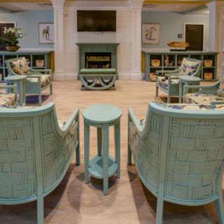 A cozy living room with pastel-colored furniture arranged around a central fireplace and television.