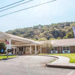 A view of a building entrance with a driveway, surrounded by hills and trees.