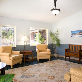 A cozy living room featuring plush yellow chairs, a wooden bench, and ample natural light.