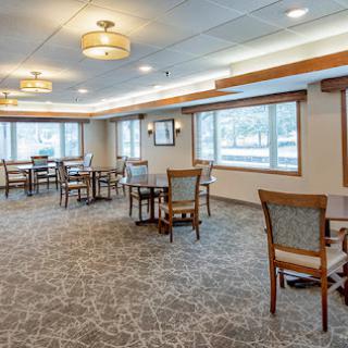 A spacious dining area with tables and chairs, featuring natural light from large windows.