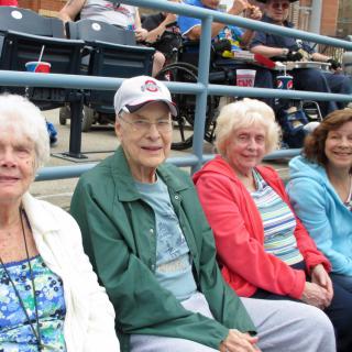A group of elderly people sitting outdoors in casual clothing.