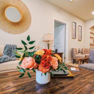 A stylish living room with a vibrant floral arrangement on a wooden table, featuring modern decor and cozy seating.