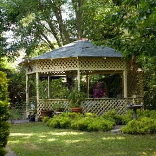A peaceful garden scene featuring a charming gazebo surrounded by lush greenery.