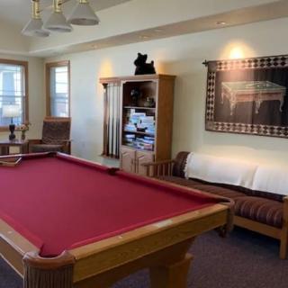 A cozy recreation room featuring a red pool table, comfortable seating, and decorative elements.