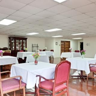 A spacious dining area with neatly arranged tables and chairs, featuring floral centerpieces.
