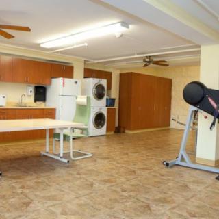 A multifunctional room featuring a laundry area, kitchenette, and exercise equipment.