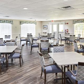 A bright and spacious dining area with multiple tables and chairs arranged on a wooden floor.