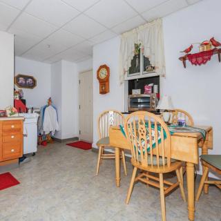 A cozy kitchen dining area with a wooden table, chairs, shelves, and decorative elements.