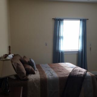 A simple bedroom with a bed, pillows, and a window with curtains.