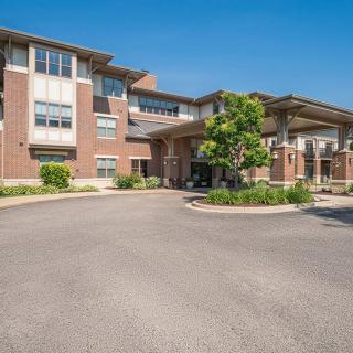A modern residential building with a circular driveway and well-maintained landscaping.