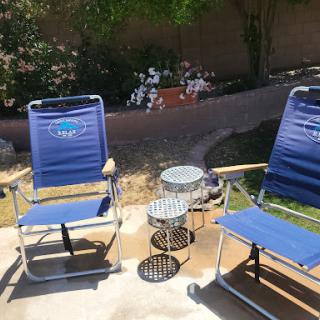 A cozy outdoor space featuring two blue reclining chairs and a small side table, perfect for relaxation.