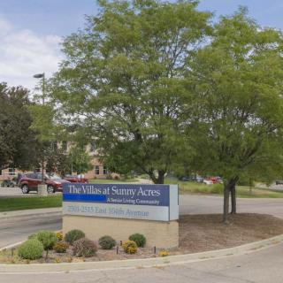 The image shows a hospital sign surrounded by trees and a landscaped area.