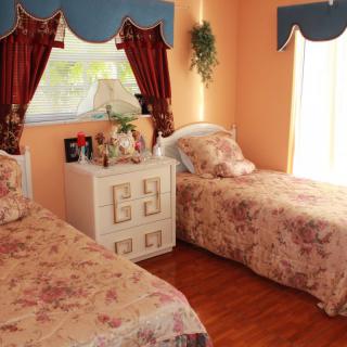 A cozy bedroom with twin beds featuring floral bedding and traditional decor.