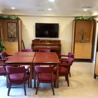 A cozy meeting room with a table, chairs, piano, and television.