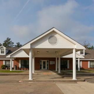 A building entrance with prominent columns and a peaked roof under a cloudy sky.