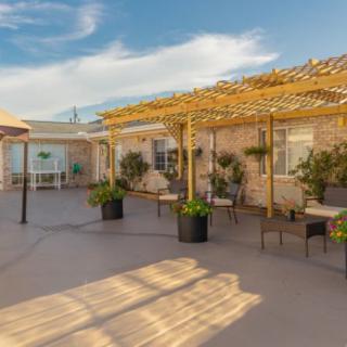 A sunny patio area featuring pergolas, outdoor furniture, and plants.