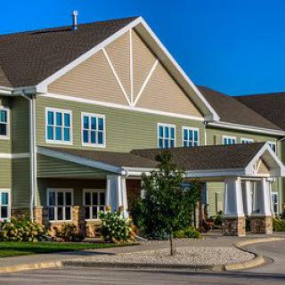 A modern residential building with a landscaped entrance under a clear blue sky.