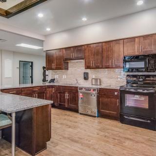 A modern kitchen with wood cabinets and an island counter, featuring sleek appliances and hardwood flooring.