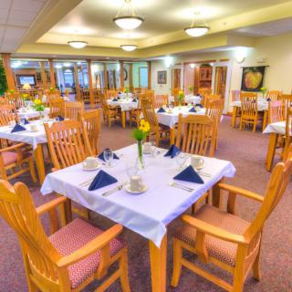 A well-arranged dining room with wooden furniture and elegantly set tables.