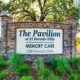 A stone sign for The Pavilion at El Dorado Hills Memory Care, surrounded by greenery.