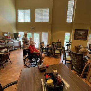 A cozy dining area with people seated and moving around, featuring tables and chairs.