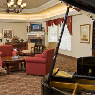 A well-decorated living room with a grand piano, comfortable seating, and a fireplace.