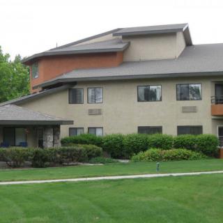 A multi-story residential building with a well-maintained lawn in front.
