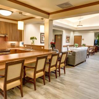 A modern open-concept kitchen and dining area with wooden furniture and sleek lighting fixtures.