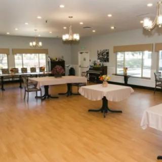 A spacious dining area with tables and chairs, illuminated by chandeliers.