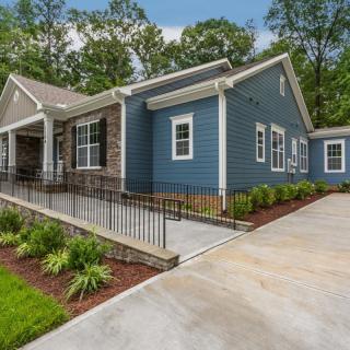 A modern single-story house with a blue exterior and landscaped garden.