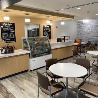 A modern cafe interior featuring a coffee bar, seating area, and an ice cream display.