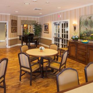 A cozy dining area with round tables and cushioned chairs, set on a polished wooden floor, adorned with wall art and decor.