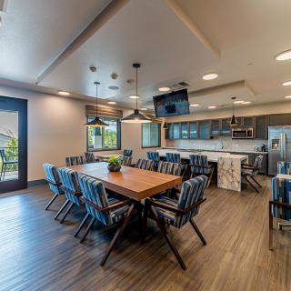 A modern dining and kitchen area with a large wooden table and stylish chairs.