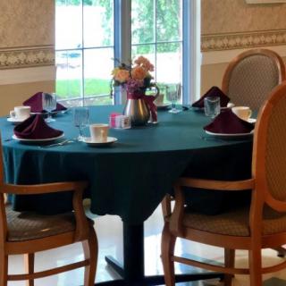 A dining table with place settings, decorated with flowers and set near a window.