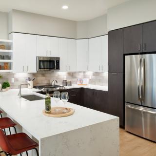 A modern kitchen with white cabinets, stainless steel appliances, and an island counter with bar stools.