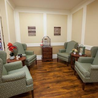 A cozy waiting room with armchairs and hardwood flooring.