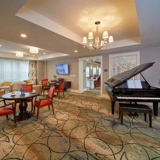 A well-appointed living room featuring a grand piano, elegant chandelier, and comfortable seating arrangements.