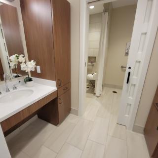 A modern bathroom with a vanity area, featuring wooden cabinets and a tiled floor.