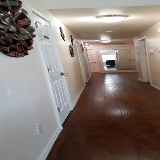 A tidy hallway with wooden floors and several doors leading to different rooms.