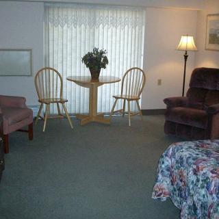 A cozy living room setup with a table and chairs, comfortable armchairs, a lamp, and decorative elements.