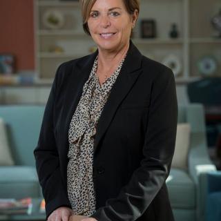 A professional woman standing indoors in an office setting.
