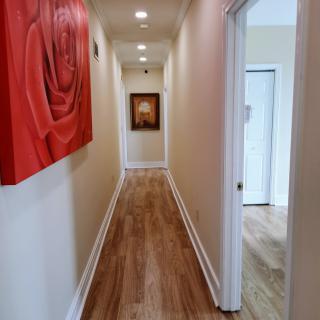 A well-lit hallway with wooden flooring and decorative artwork on the walls.