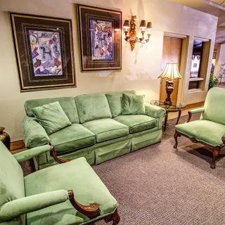 A cozy living room featuring green upholstered furniture and wall art.
