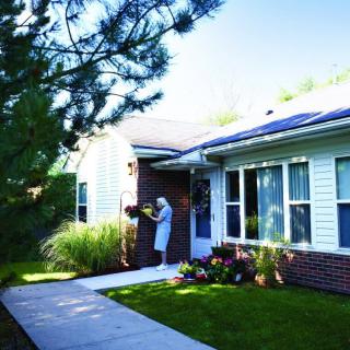 A person tending to the garden outside a house with solar panels on the roof.