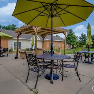 A cozy outdoor patio with tables and chairs under large green umbrellas on a sunny day.
