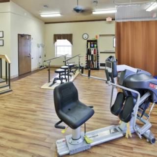 A rehabilitation room featuring various exercise equipment and a wooden floor.