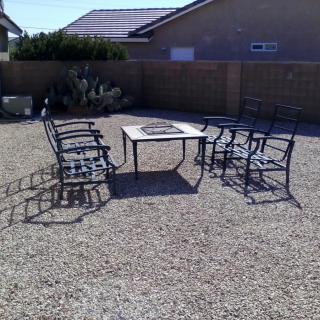 Outdoor patio set with chairs and table on a gravel yard.